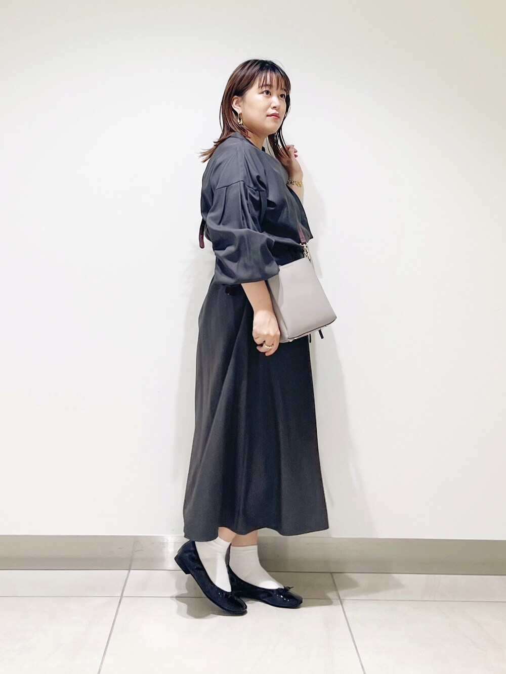 グレー系のワンピース、グレー系のショルダーバッグ、ブラック系のバレエシューズを着用したレディースの秋コーディネートの5枚目の写真