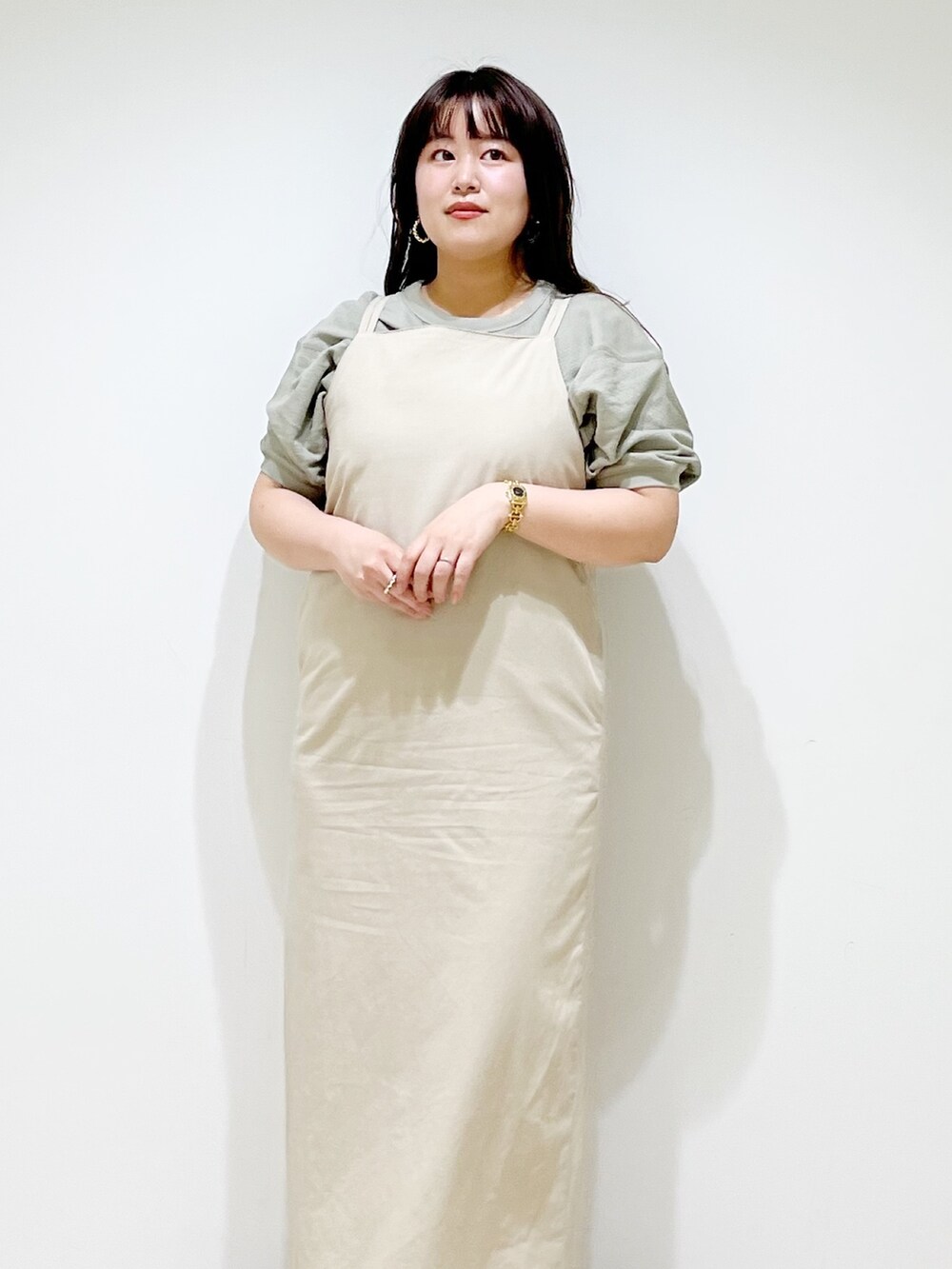 ベージュ系のワンピース、シルバー系のサンダル、グリーン系のTシャツ/カットソーを着用したレディースの春コーディネートの5枚目の写真