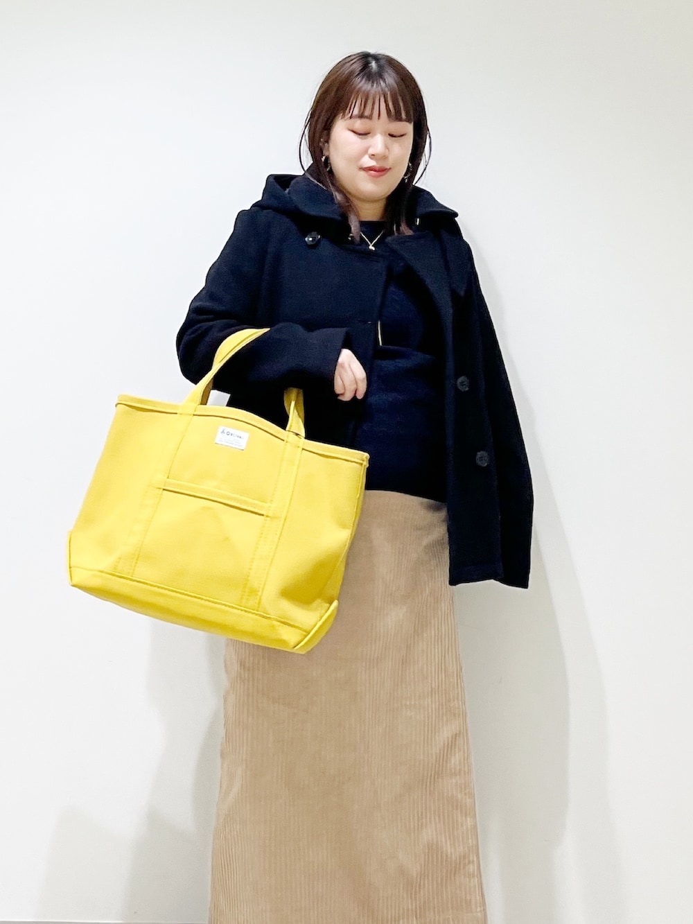 ブラック系のピーコート、ブルー系のニット/セーター、ブラック系のローファーを着用したレディースの冬コーディネートの6枚目の写真