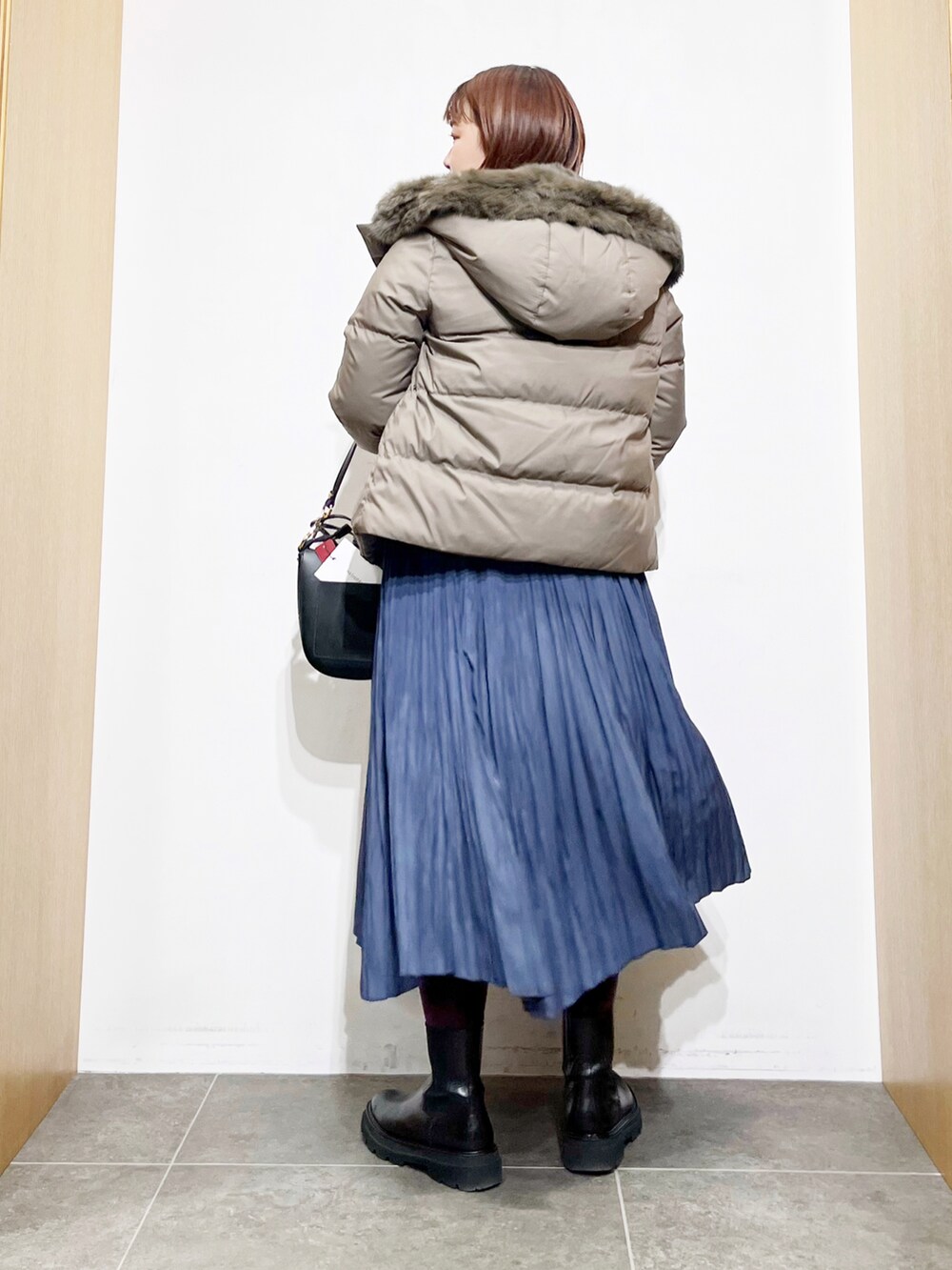 グリーン系のダウンジャケット/コート、ベージュ系のニット/セーター、ブラック系のショルダーバッグを着用したレディースの冬コーディネートの2枚目の写真