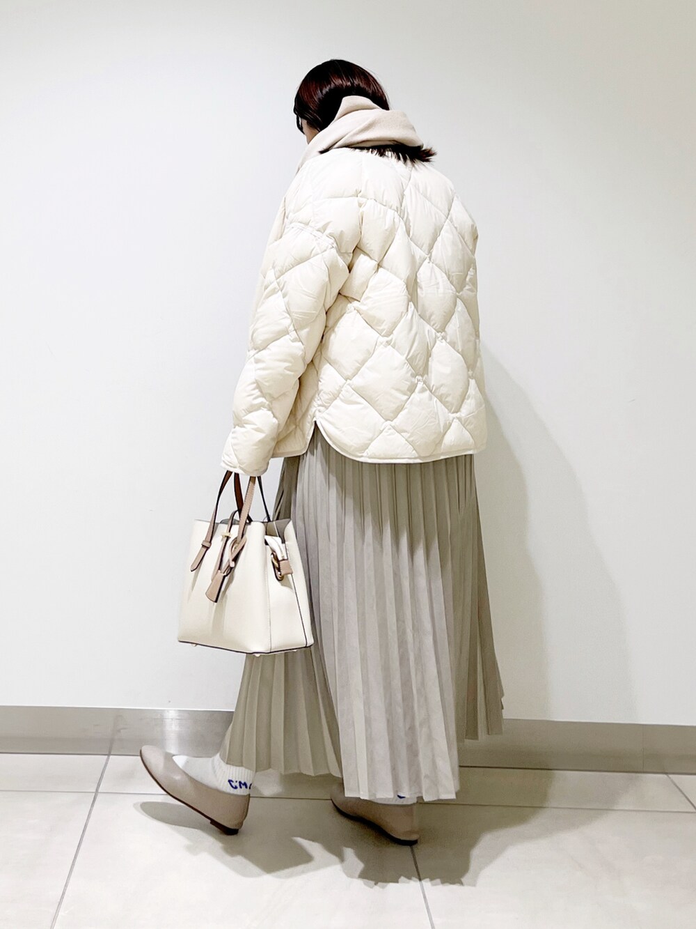 ホワイト系のダウンジャケット/コート、グレー系のニット/セーター、ベージュ系のスカートを着用したレディースの冬コーディネートの5枚目の写真