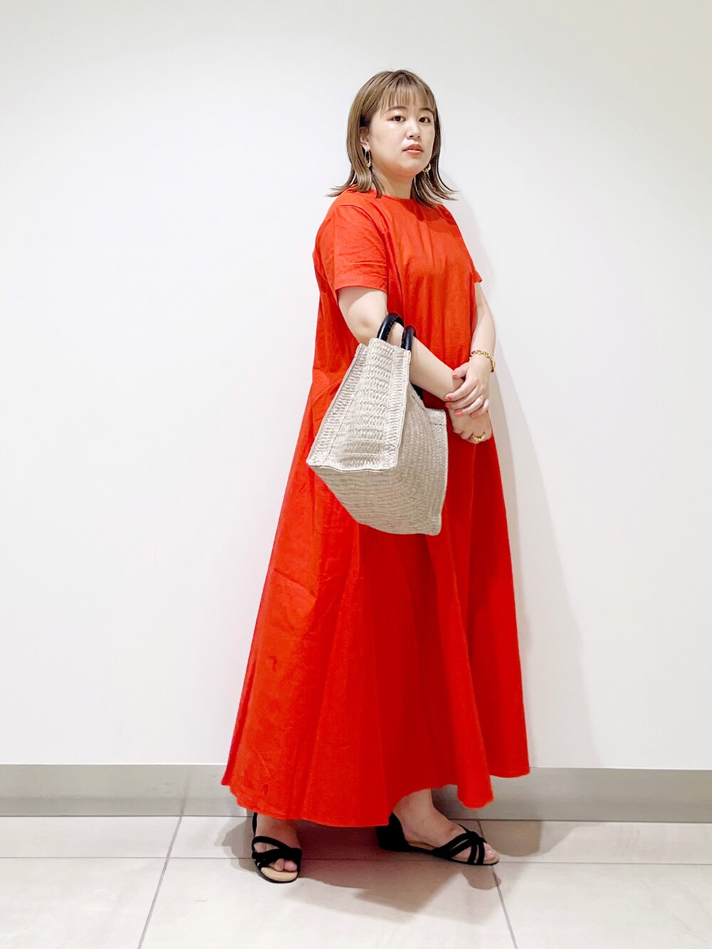 レッド系のワンピース、ベージュ系のトートバッグ、ブラック系のサンダルを着用したレディースの夏コーディネートの3枚目の写真