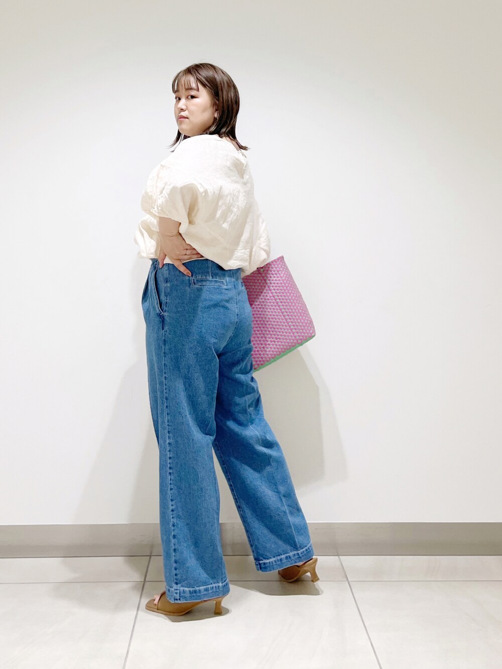 ベージュ系のシャツ/ブラウス、ピンク系のトートバッグ、ブルー系のデニムパンツを着用したレディースの春コーディネートの4枚目の写真