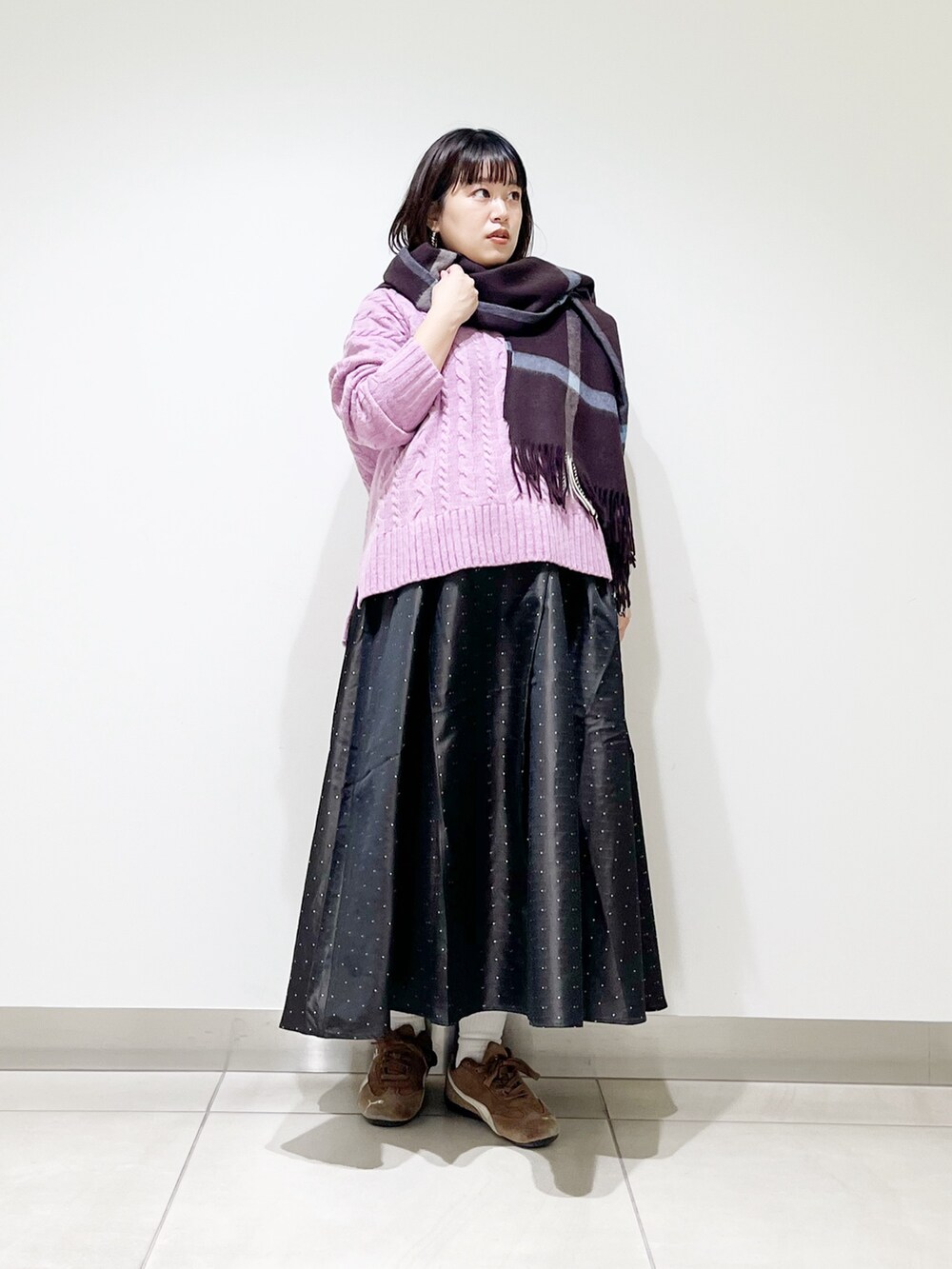 パープル系のニット/セーター、ブルー系のスカート、ブラック系のスニーカーを着用したレディースの秋コーディネートの8枚目の写真