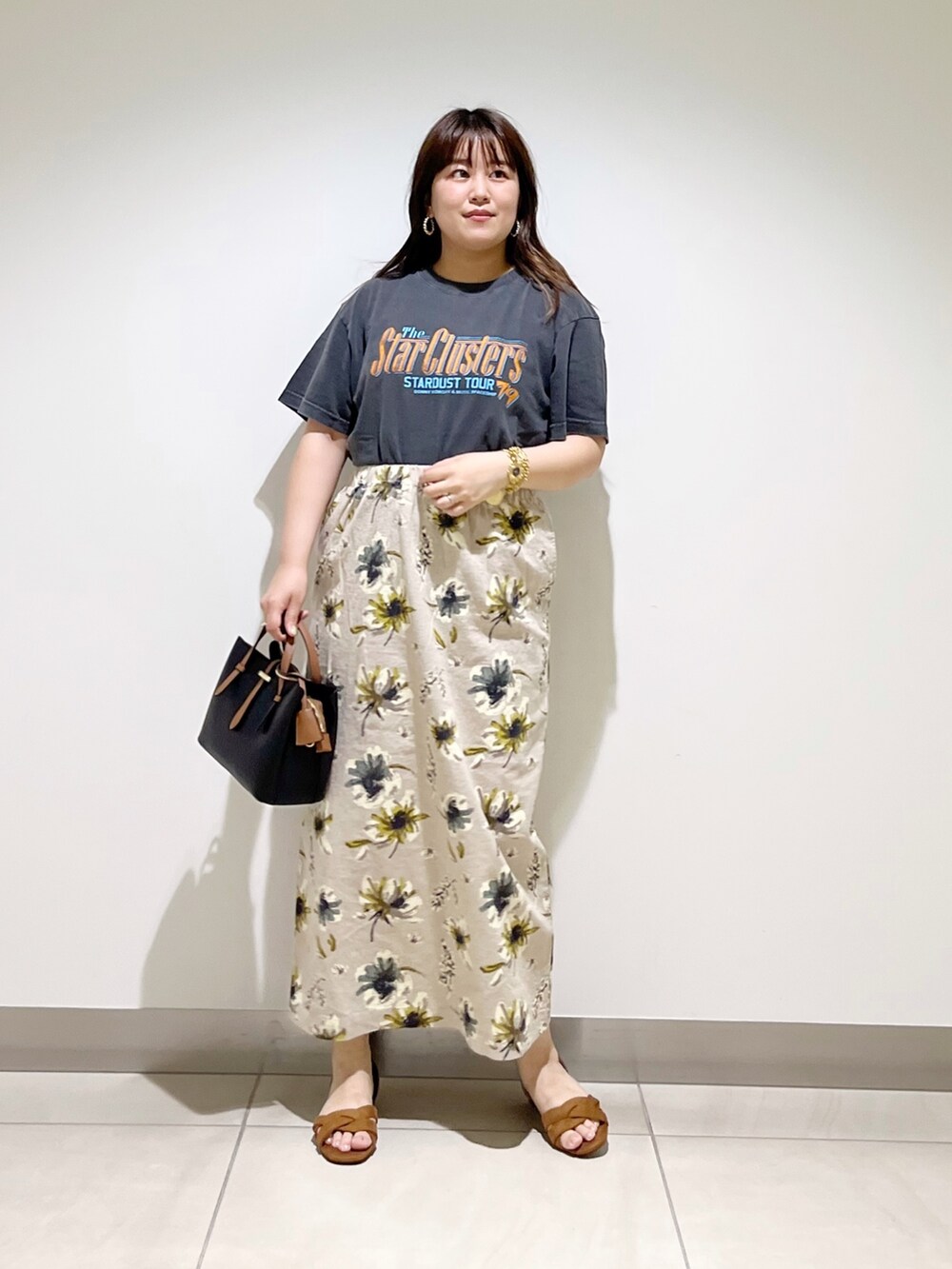 オレンジ系のTシャツ/カットソー、ブラック系のハンドバッグ、イエロー系のスカートを着用したレディースの夏コーディネートの2枚目の写真