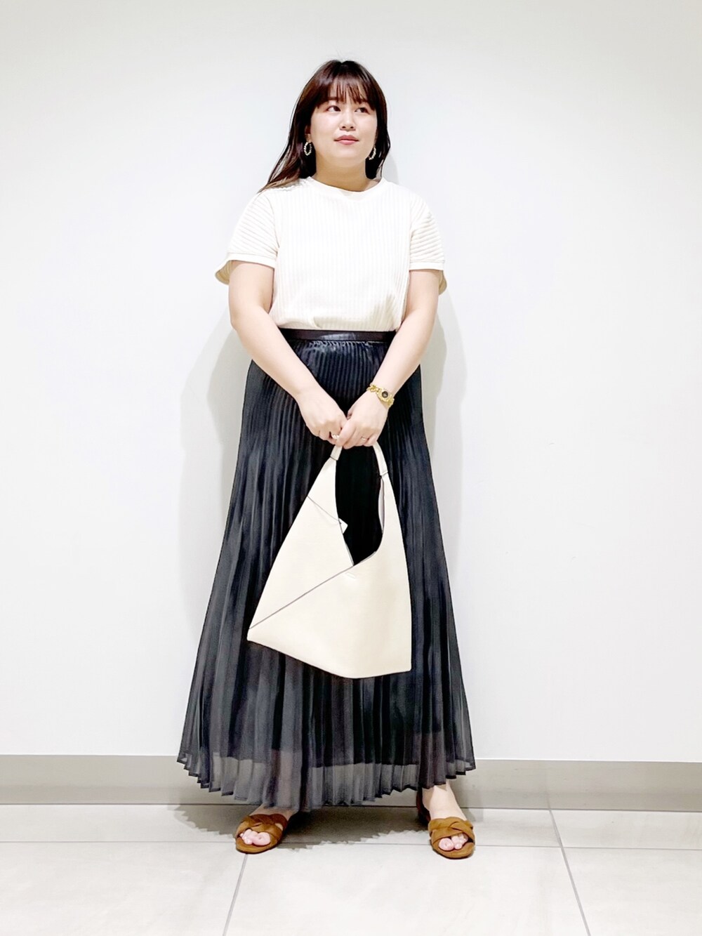 ホワイト系のニット/セーター、ホワイト系のトートバッグ、ブラック系のスカートを着用したレディースの夏コーディネートの2枚目の写真