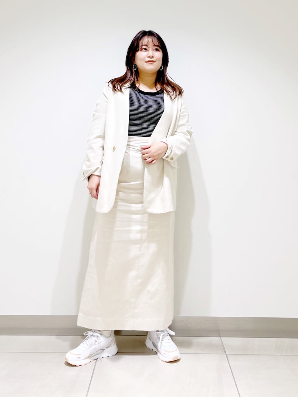 ベージュ系のスカート、ベージュ系のノーカラージャケット、ホワイト系のTシャツ/カットソーを着用したレディースの春コーディネートの2枚目の写真