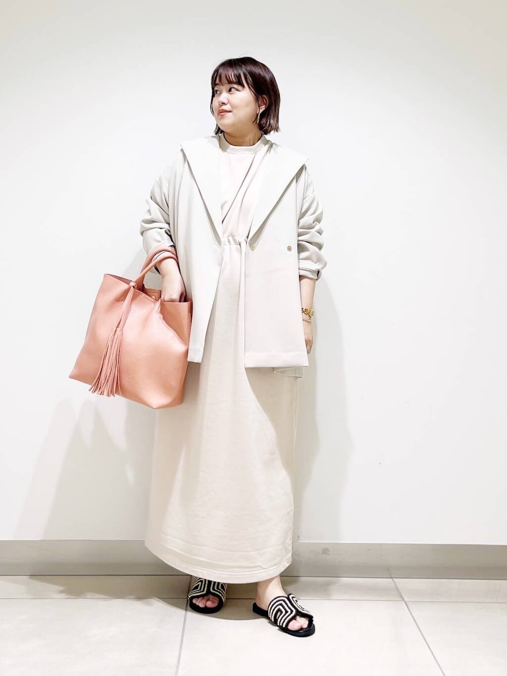 ピンク系のトートバッグ、ベージュ系のその他アウター、ベージュ系のワンピースを着用したレディースの春コーディネートの2枚目の写真