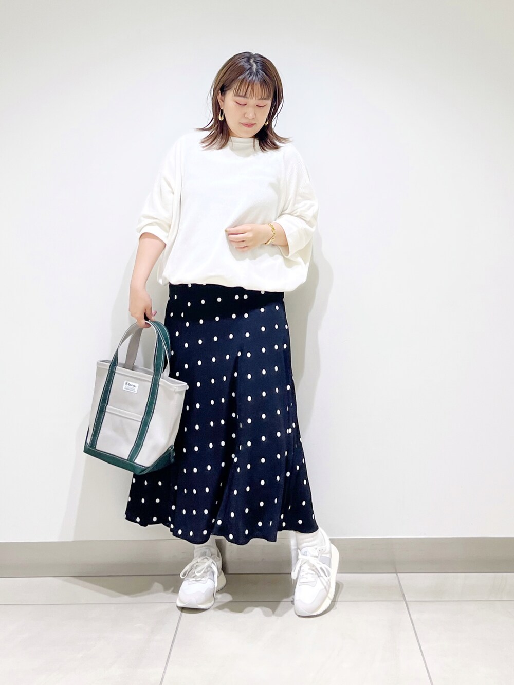 ブラック系のスカート、ホワイト系のTシャツ/カットソー、グリーン系のトートバッグを着用したレディースの夏コーディネートの5枚目の写真