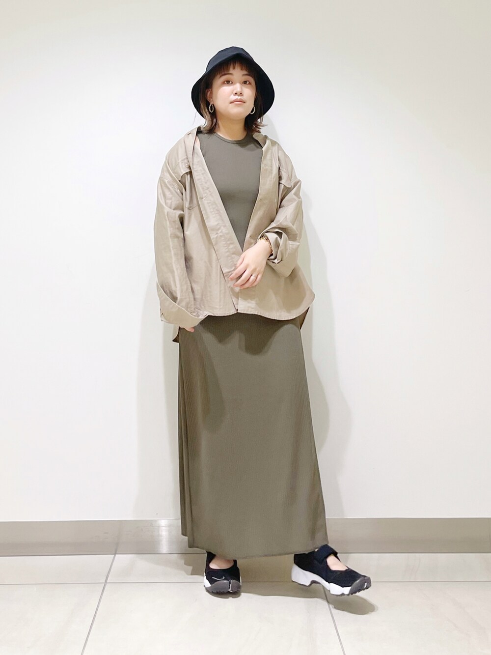 グリーン系のワンピース、ベージュ系のシャツ/ブラウス、ブラック系のスニーカーを着用したレディースの春コーディネートの4枚目の写真