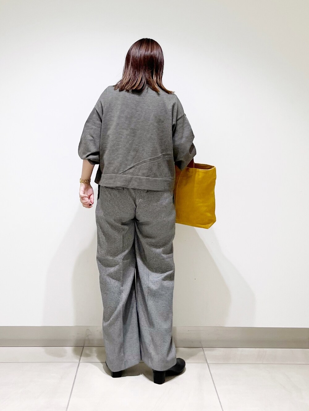 グレー系のニット/セーター、ベージュ系のパンツ、イエロー系のトートバッグを着用したレディースの秋コーディネートの7枚目の写真
