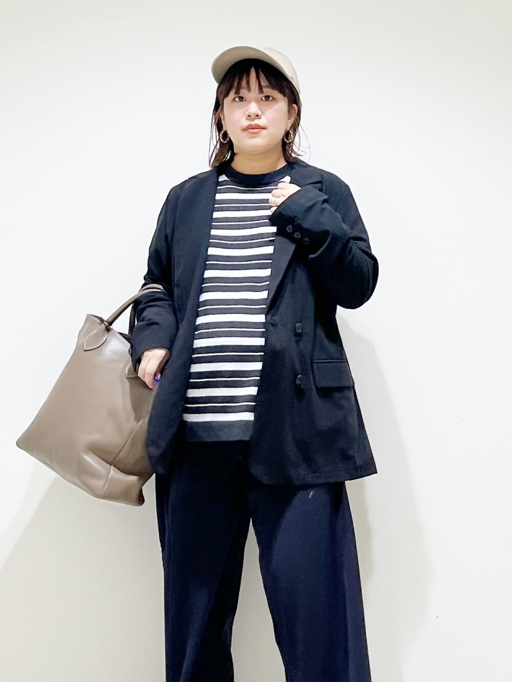 ブラック系のその他アウター、グレー系のニット/セーター、グレー系のトートバッグを着用したレディースの秋コーディネートの2枚目の写真