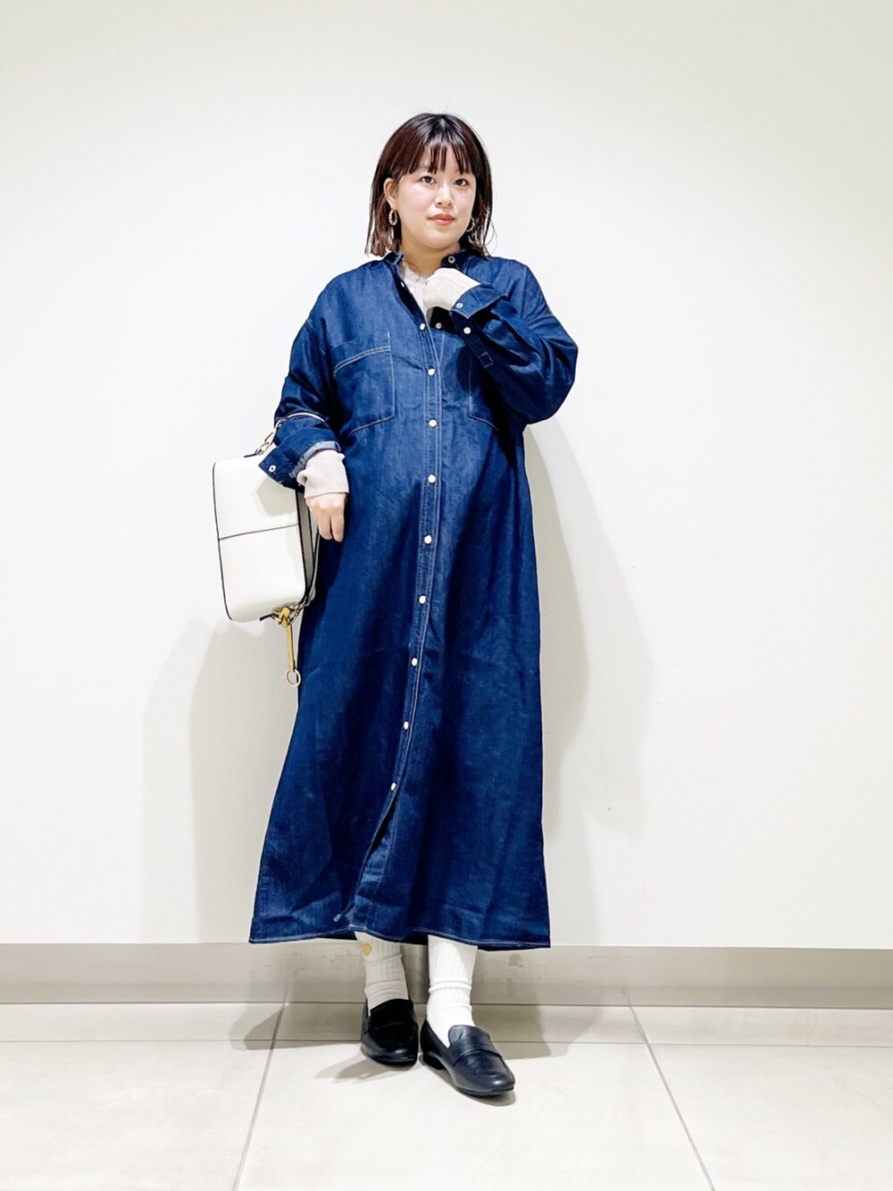 ブルー系のワンピース、ベージュ系のニット/セーター、ホワイト系のショルダーバッグを着用したレディースの秋コーディネートの2枚目の写真