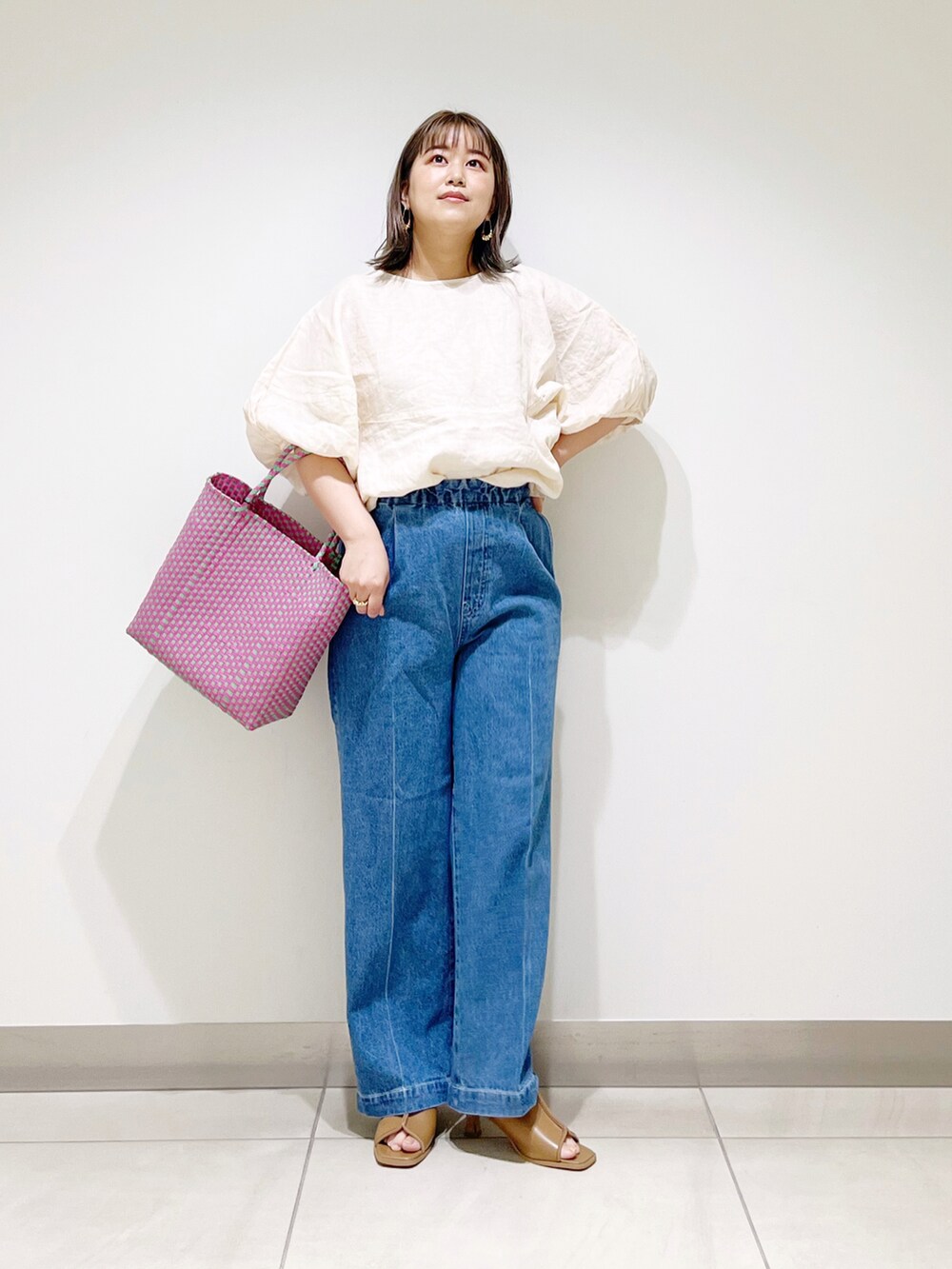 ベージュ系のシャツ/ブラウス、ピンク系のトートバッグ、ブルー系のデニムパンツを着用したレディースの春コーディネートの2枚目の写真