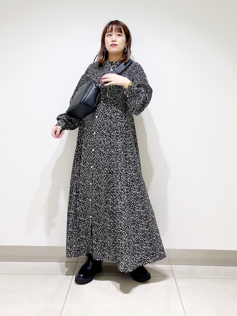 ブラック系のシャツワンピース、ブラック系のショルダーバッグ、ブラック系のブーツを着用したレディースの秋コーディネートの6枚目の写真