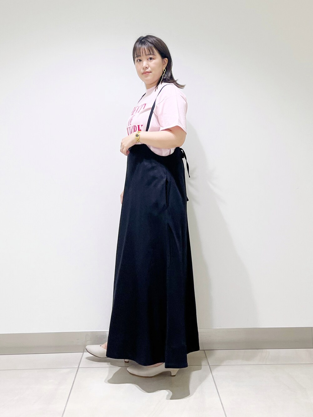 ピンク系のTシャツ/カットソー、ブラック系のスカート、ベージュ系のパンプスを着用したレディースの夏コーディネートの3枚目の写真