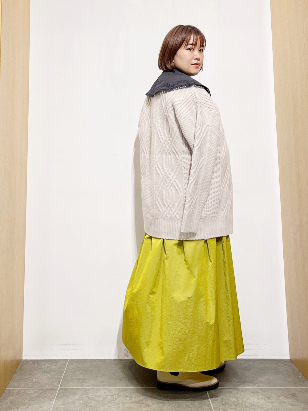 ブラック系のシャツ/ブラウス、ベージュ系のカーディガン/ボレロ、イエロー系のスカートを着用したレディースの秋コーディネートの4枚目の写真