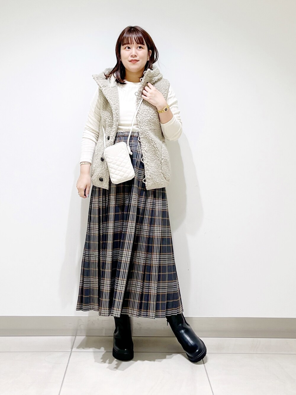 ホワイト系のトップス、グレー系のスカート、ブラック系のブーツを着用したレディースの秋コーディネートの9枚目の写真