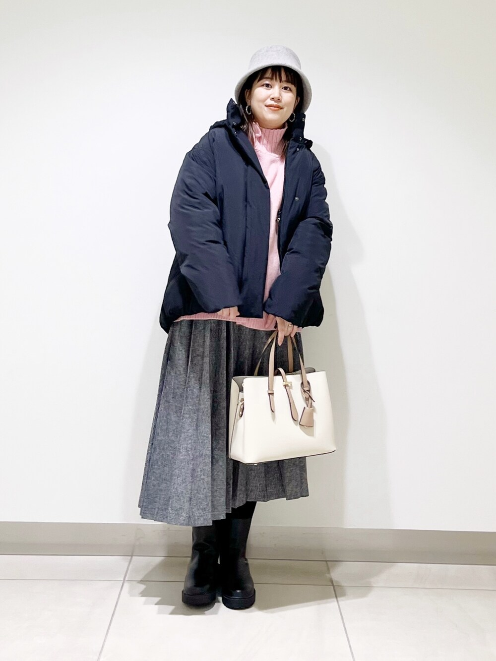 ブラック系のダウンジャケット/コート、ピンク系のニット/セーター、ブルー系のスカートを着用したレディースの冬コーディネートの10枚目の写真