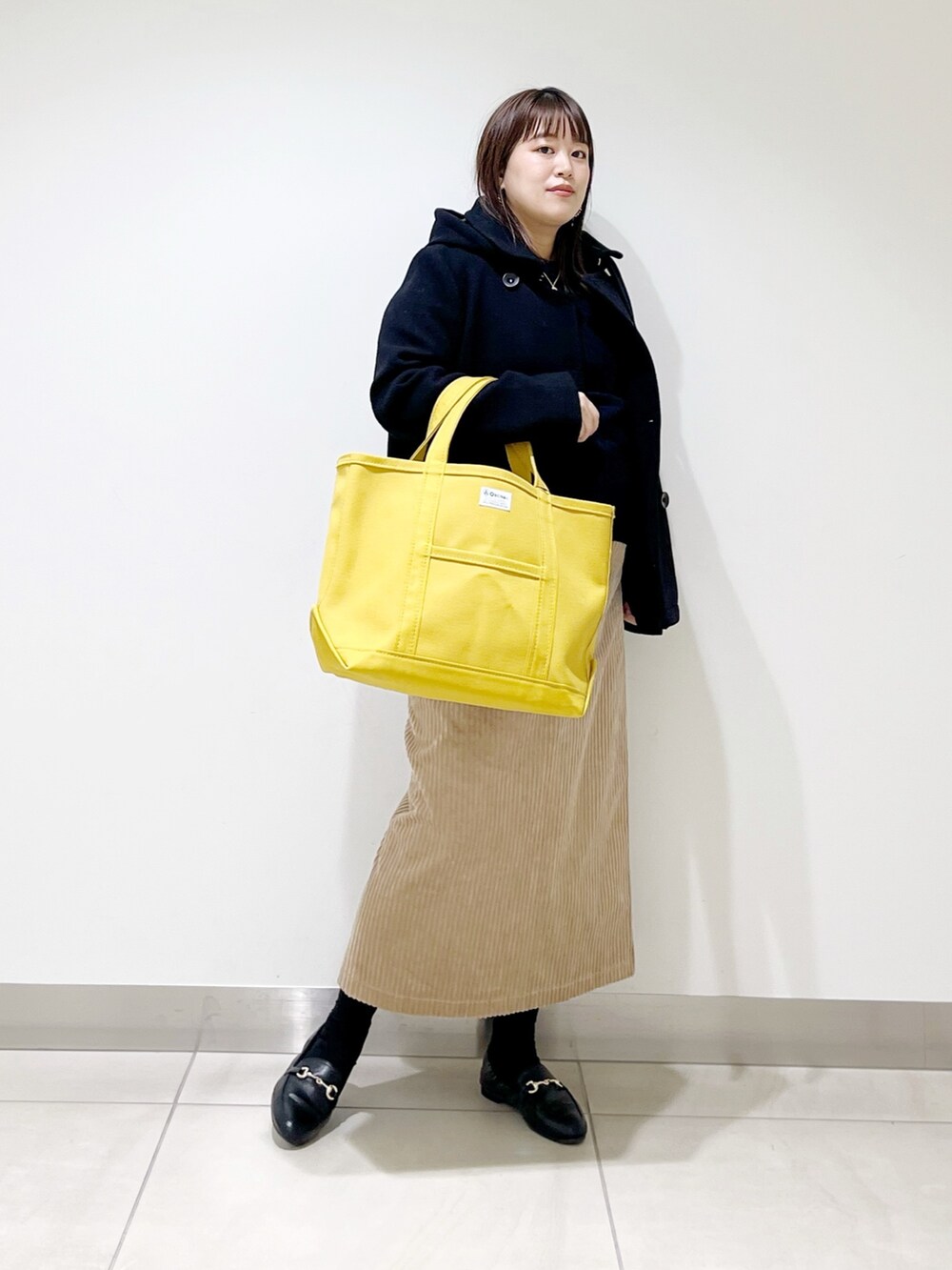 ブラック系のピーコート、ブルー系のニット/セーター、ブラック系のローファーを着用したレディースの冬コーディネートの8枚目の写真