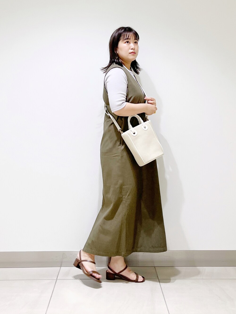 グレー系のワンピース、ベージュ系のショルダーバッグ、ブラック系のサンダルを着用したレディースの夏コーディネートの3枚目の写真