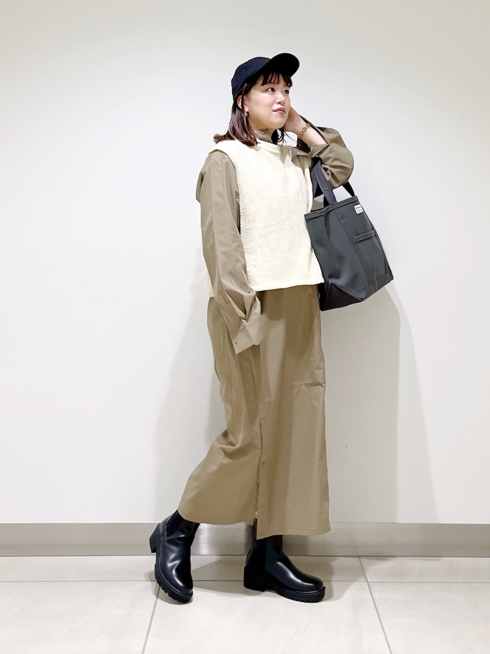 ホワイト系のベスト、グリーン系のワンピース、グレー系のトートバッグを着用したレディースの秋コーディネートの8枚目の写真