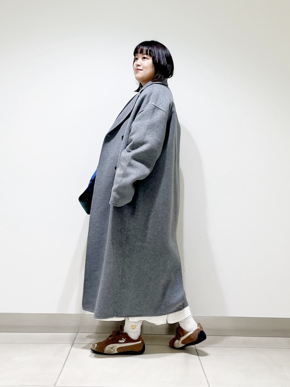 ブルー系のニット/セーター、ホワイト系のスカート、ブラック系のスニーカーを着用したレディースの秋コーディネートの6枚目の写真