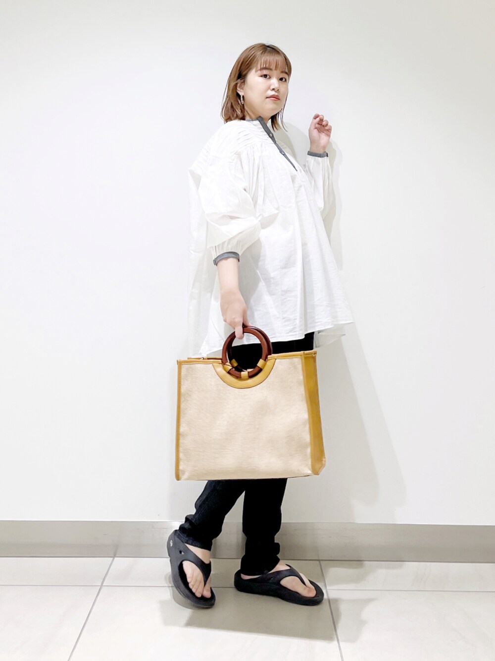 ホワイト系のシャツ/ブラウス、イエロー系のトートバッグ、ブラック系のデニムパンツを着用したレディースの春コーディネートの2枚目の写真