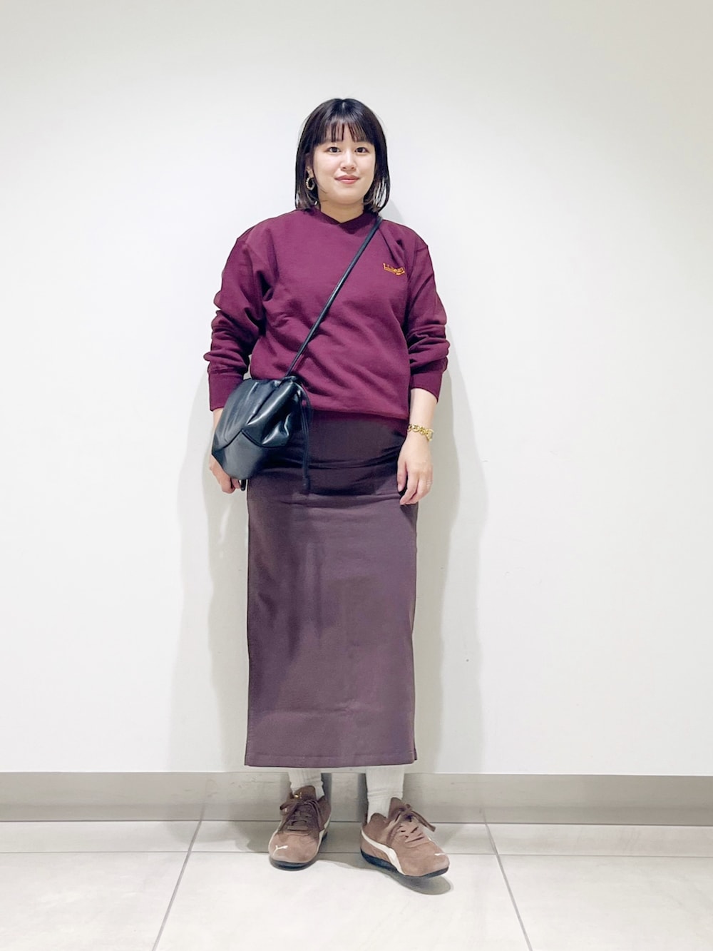 ブラウン系のスウェット、ブラウン系のスカート、ブラック系のスニーカーを着用したレディースの秋コーディネートの2枚目の写真