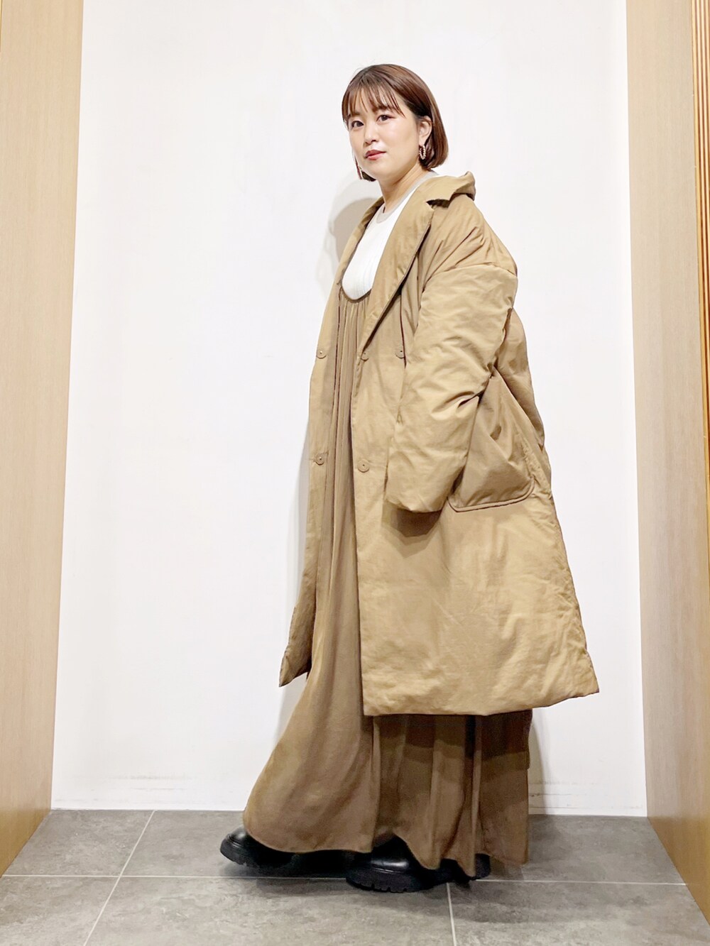 ベージュ系のダウンジャケット/コート、ブラウン系のワンピース、ホワイト系のニット/セーターを着用したレディースの秋コーディネートの3枚目の写真