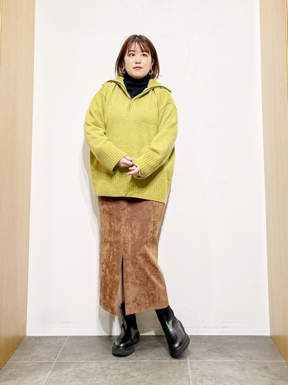 グリーン系のニット/セーター、ブラック系のニット/セーター、ブラウン系のスカートを着用したレディースの冬コーディネートの5枚目の写真