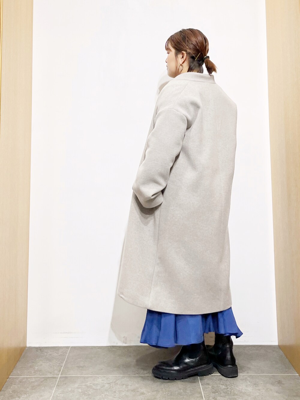 グレー系のその他アウター、ブルー系のスカート、ブラック系のブーツを着用したレディースの冬コーディネートの5枚目の写真