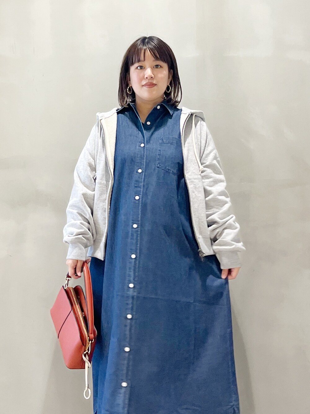 ブルー系のワンピース、オレンジ系のショルダーバッグ、ブラック系のスニーカーを着用したレディースの秋コーディネートの3枚目の写真