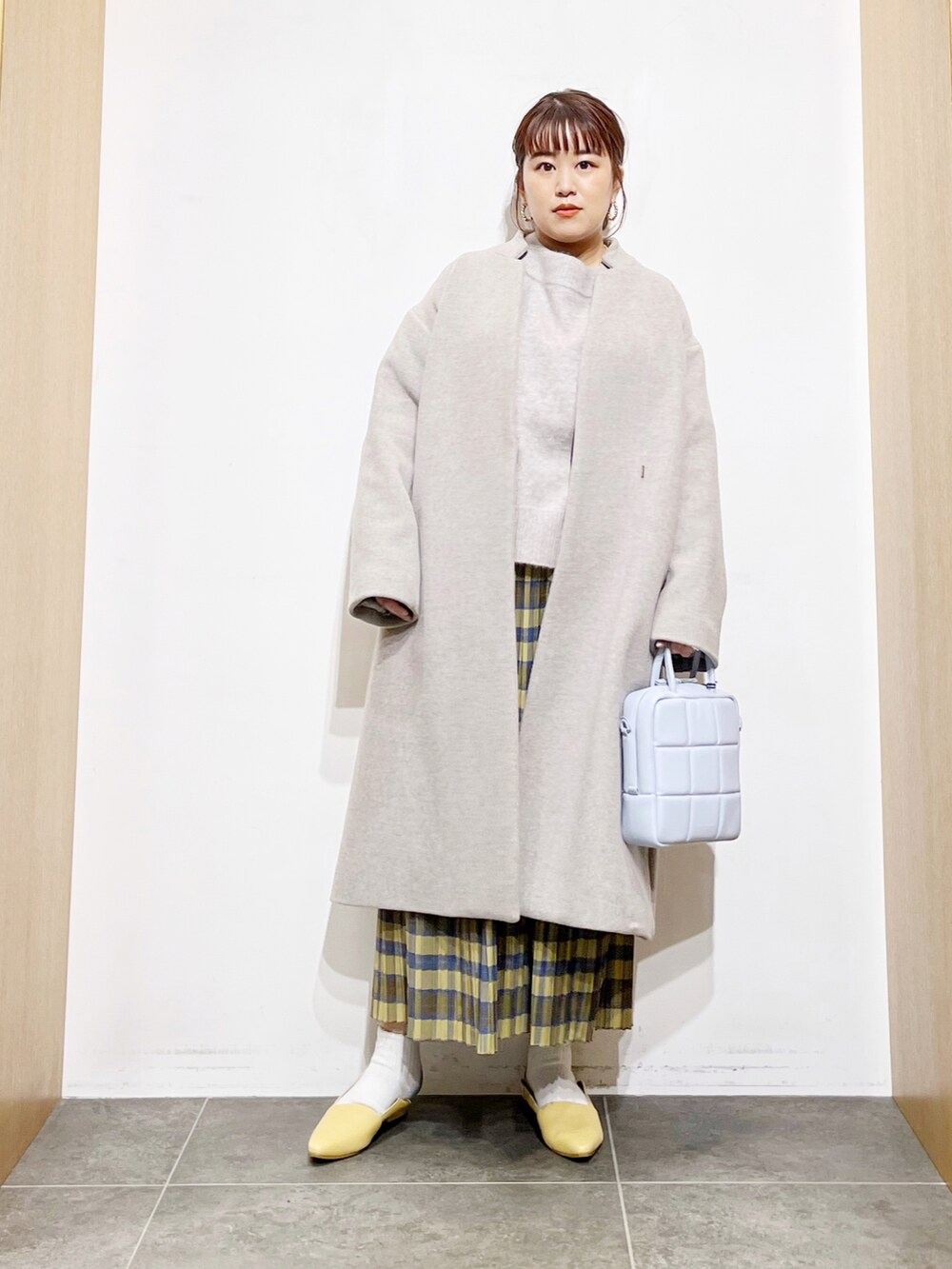 ベージュ系のニット/セーター、グレー系のその他アウター、イエロー系のスカートを着用したレディースの冬コーディネートの5枚目の写真