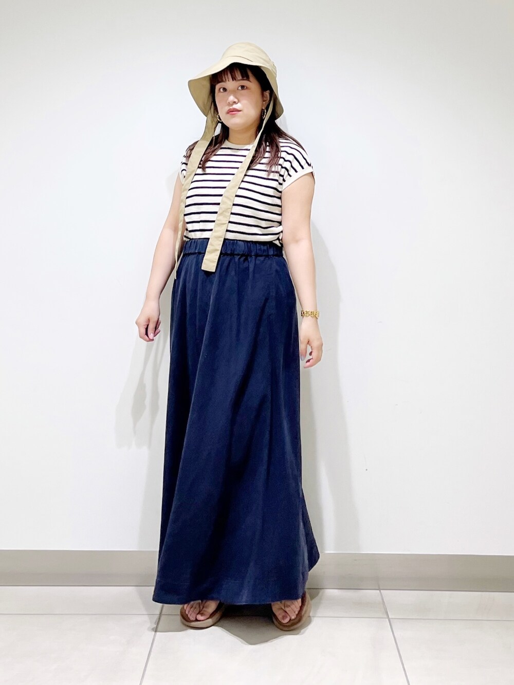 ベージュ系のTシャツ/カットソー、ブルー系のスカート、ベージュ系のサンダルを着用したレディースの夏コーディネートの3枚目の写真