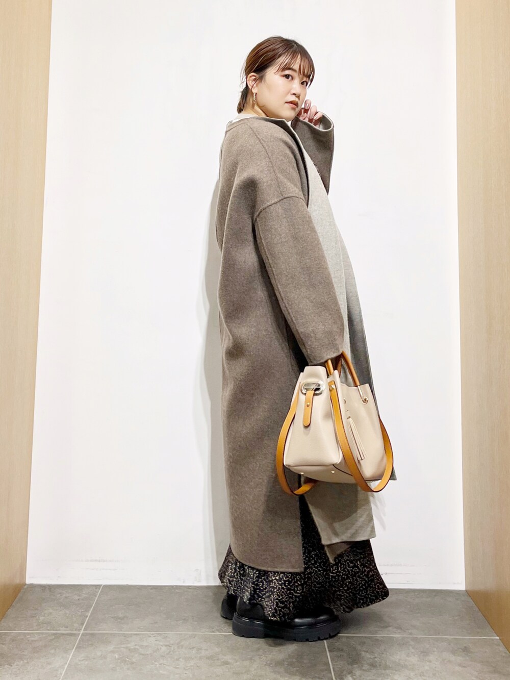 グレー系のその他アウター、ブラック系のワンピース、ベージュ系のトートバッグを着用したレディースの秋コーディネートの2枚目の写真
