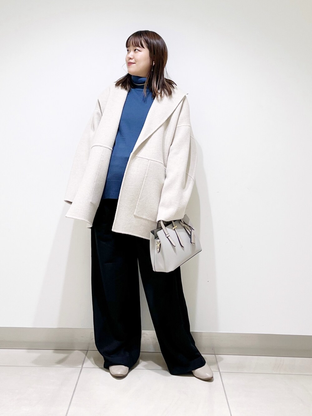 ベージュ系のその他アウター、ブルー系のニット/セーター、ブラック系のパンプスを着用したレディースの冬コーディネートの2枚目の写真