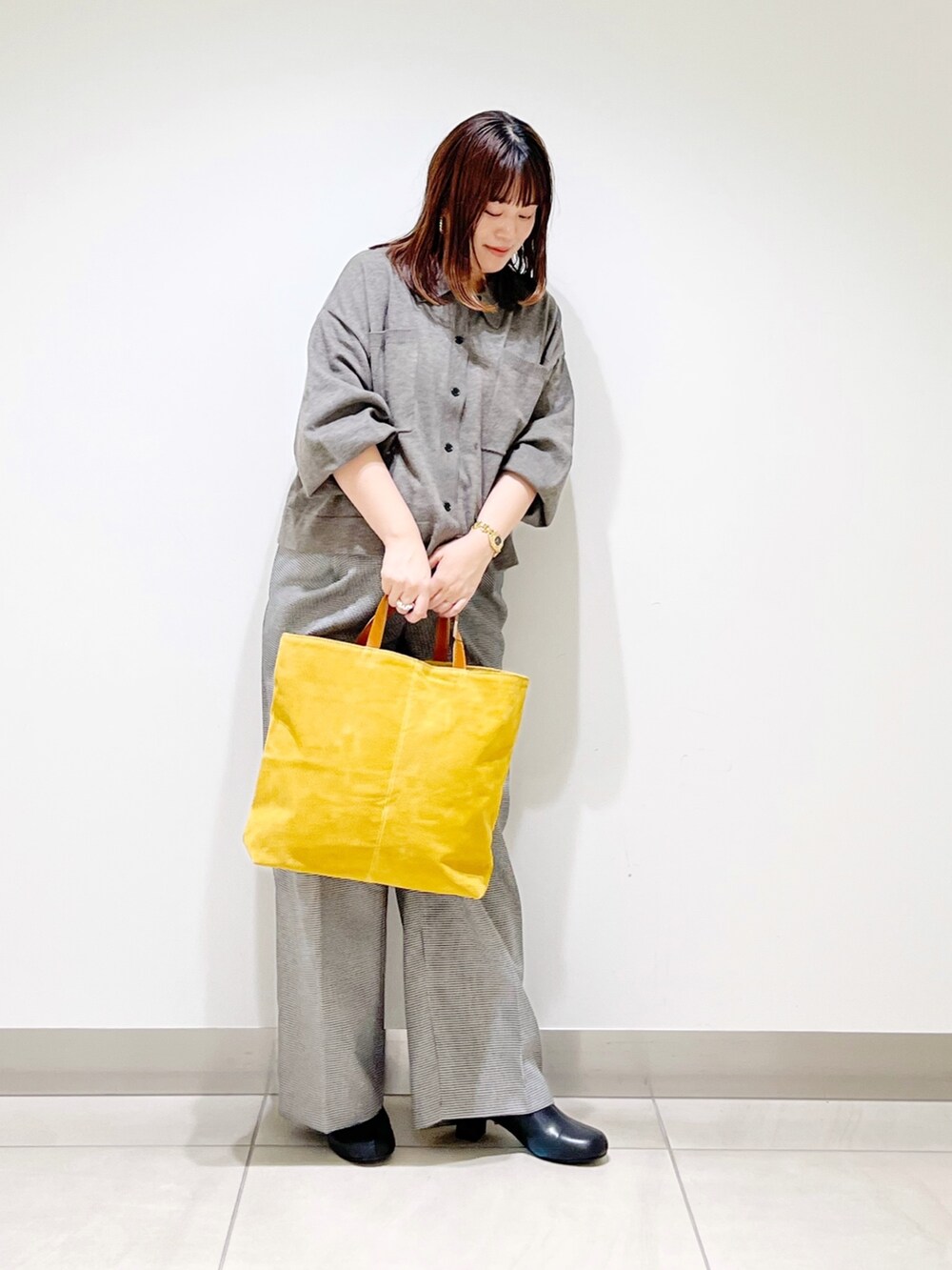 グレー系のニット/セーター、ベージュ系のパンツ、イエロー系のトートバッグを着用したレディースの秋コーディネートの9枚目の写真