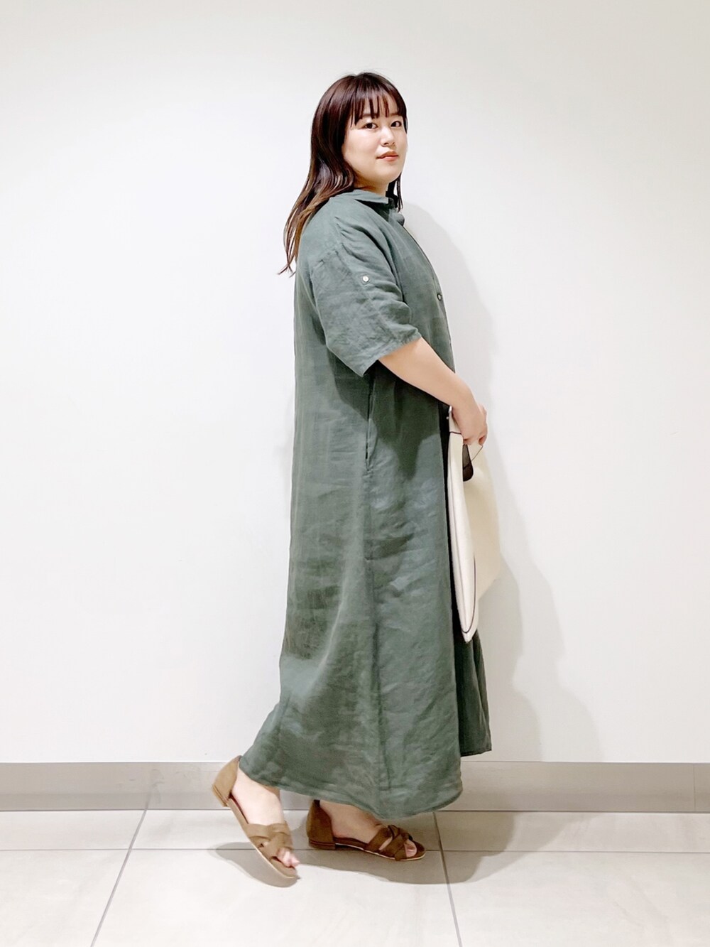 グリーン系のワンピース、ホワイト系のトートバッグ、ベージュ系のサンダルを着用したレディースの春コーディネートの6枚目の写真