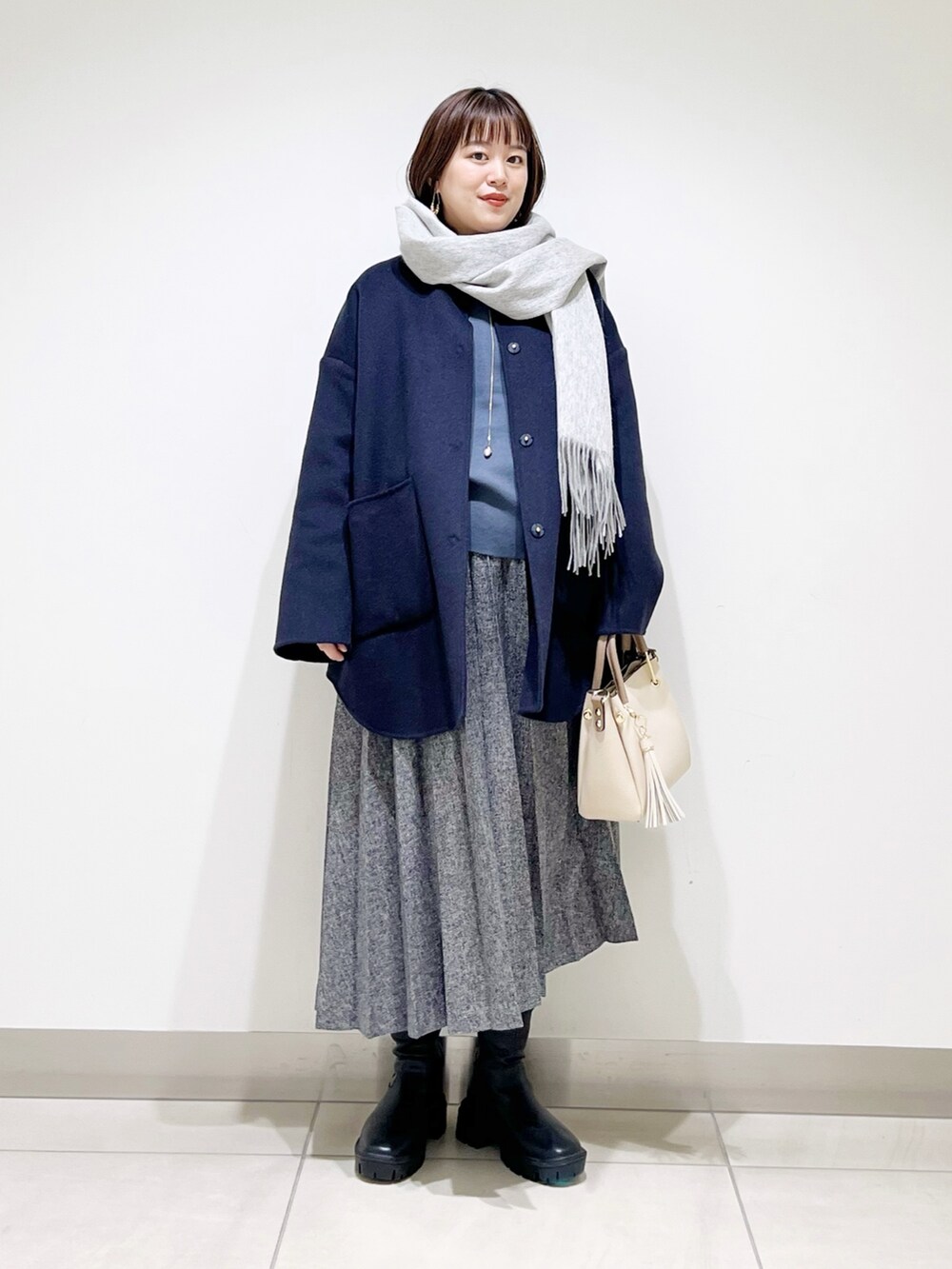 ブルー系のノーカラージャケット、グレー系のニット/セーター、ブルー系のスカートを着用したレディースの秋コーディネートの9枚目の写真