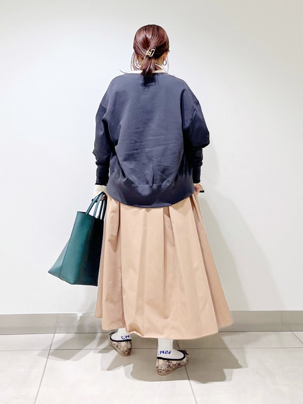 グリーン系のトートバッグ、ベージュ系のスカート、その他のバレエシューズを着用したレディースの秋コーディネートの7枚目の写真