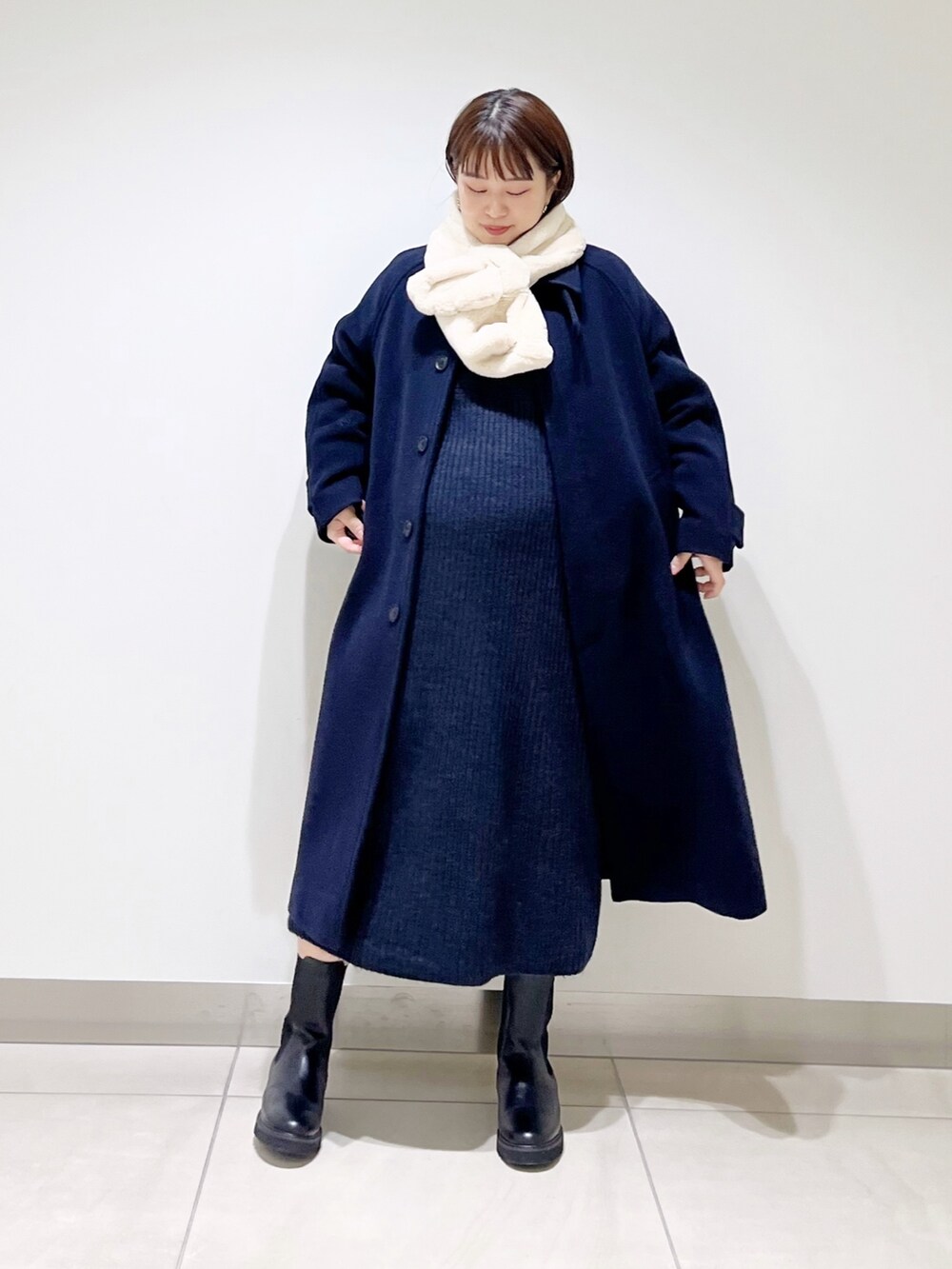 ブルー系のステンカラーコート、ブルー系のワンピース、ブラック系のブーツを着用したレディースの冬コーディネートの9枚目の写真