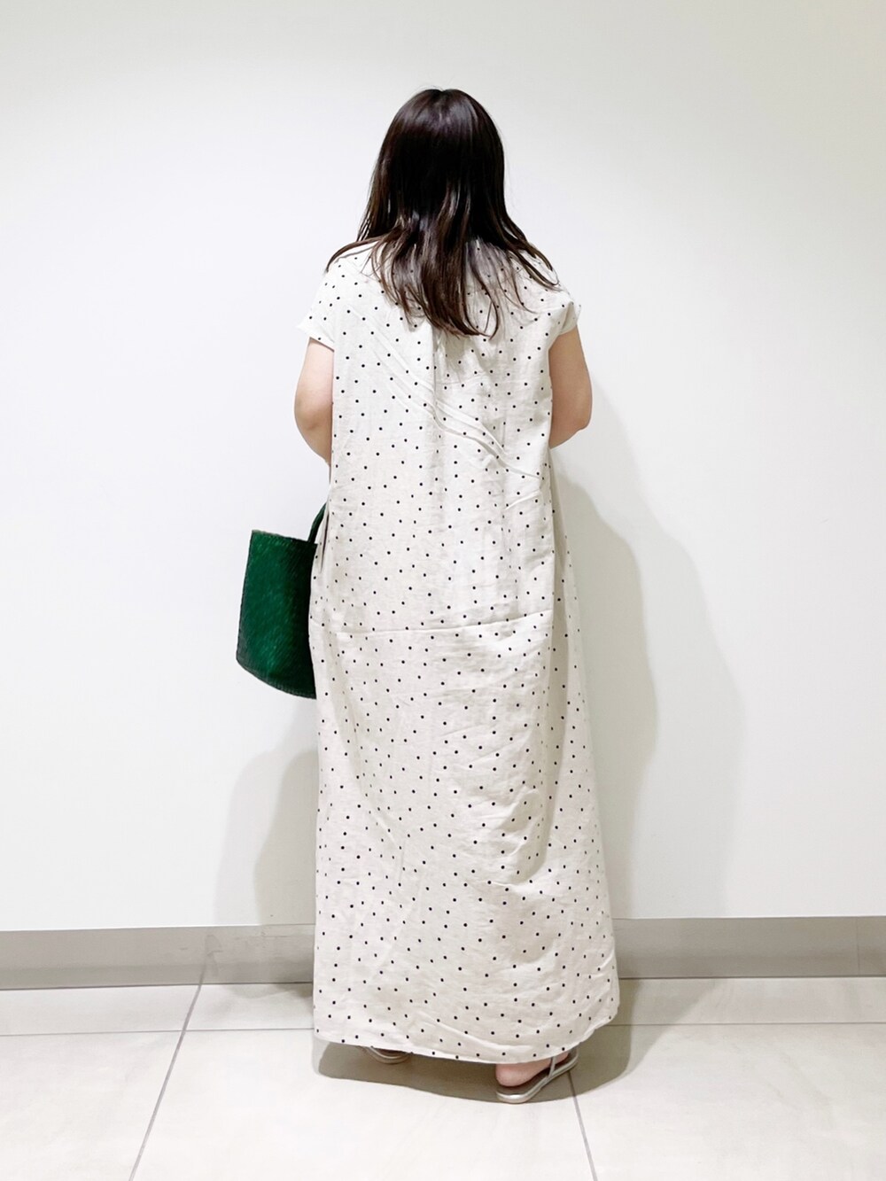 ベージュ系のワンピース、グリーン系のハンドバッグ、シルバー系のサンダルを着用したレディースの春コーディネートの2枚目の写真