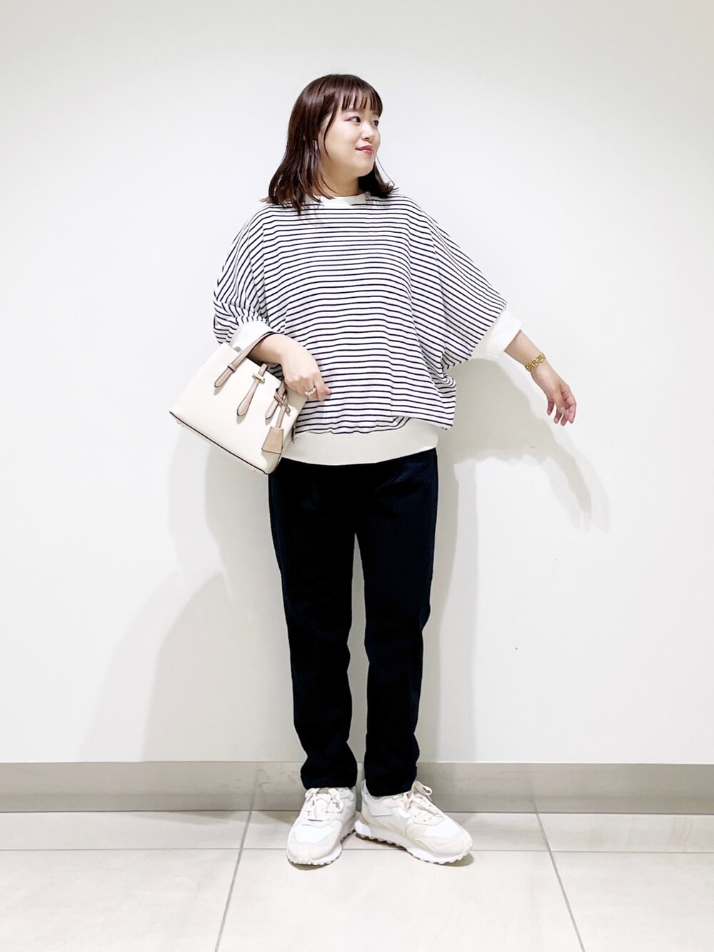 ホワイト系のTシャツ/カットソー、ブルー系のパンツ、ホワイト系のハンドバッグを着用したレディースの秋コーディネートの3枚目の写真