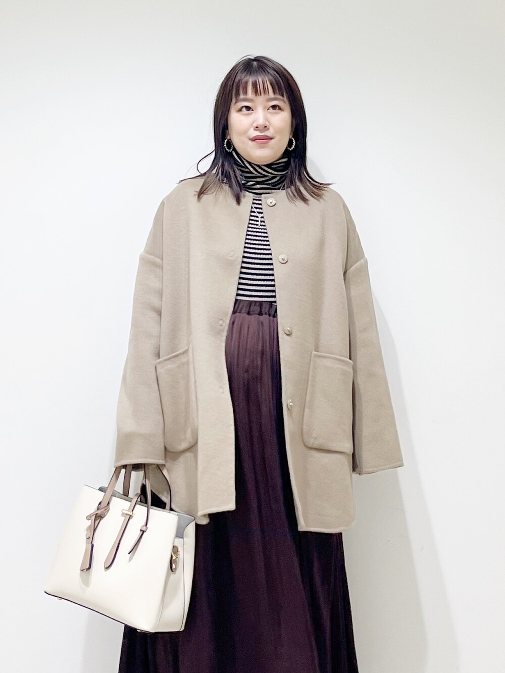 ベージュ系のノーカラージャケット、ブラウン系のニット/セーター、ブラウン系のスカートを着用したレディースの秋コーディネートの7枚目の写真