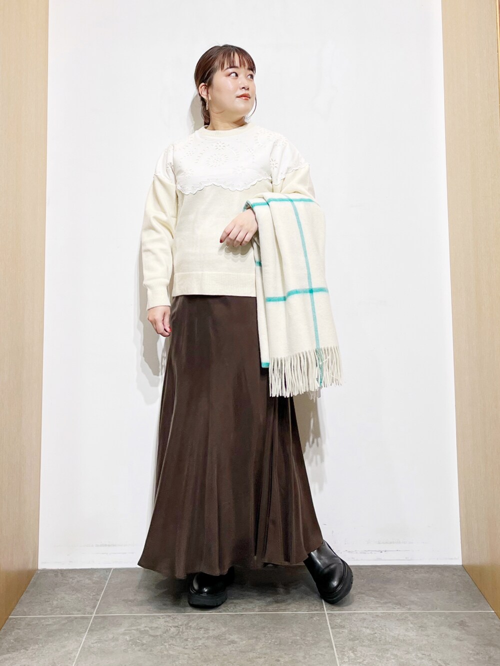 ブラウン系のスカート、ホワイト系のニット/セーター、ブラック系のブーツを着用したレディースの冬コーディネートの3枚目の写真