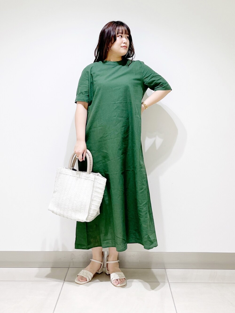 グリーン系のワンピース、ホワイト系のバッグ、ホワイト系のサンダルを着用したレディースの春コーディネートの2枚目の写真