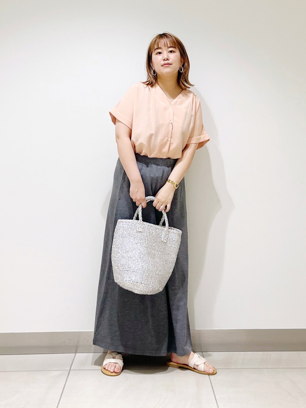 オレンジ系のシャツ/ブラウス、シルバー系のトートバッグ、グレー系のスカートを着用したレディースの春コーディネートの2枚目の写真