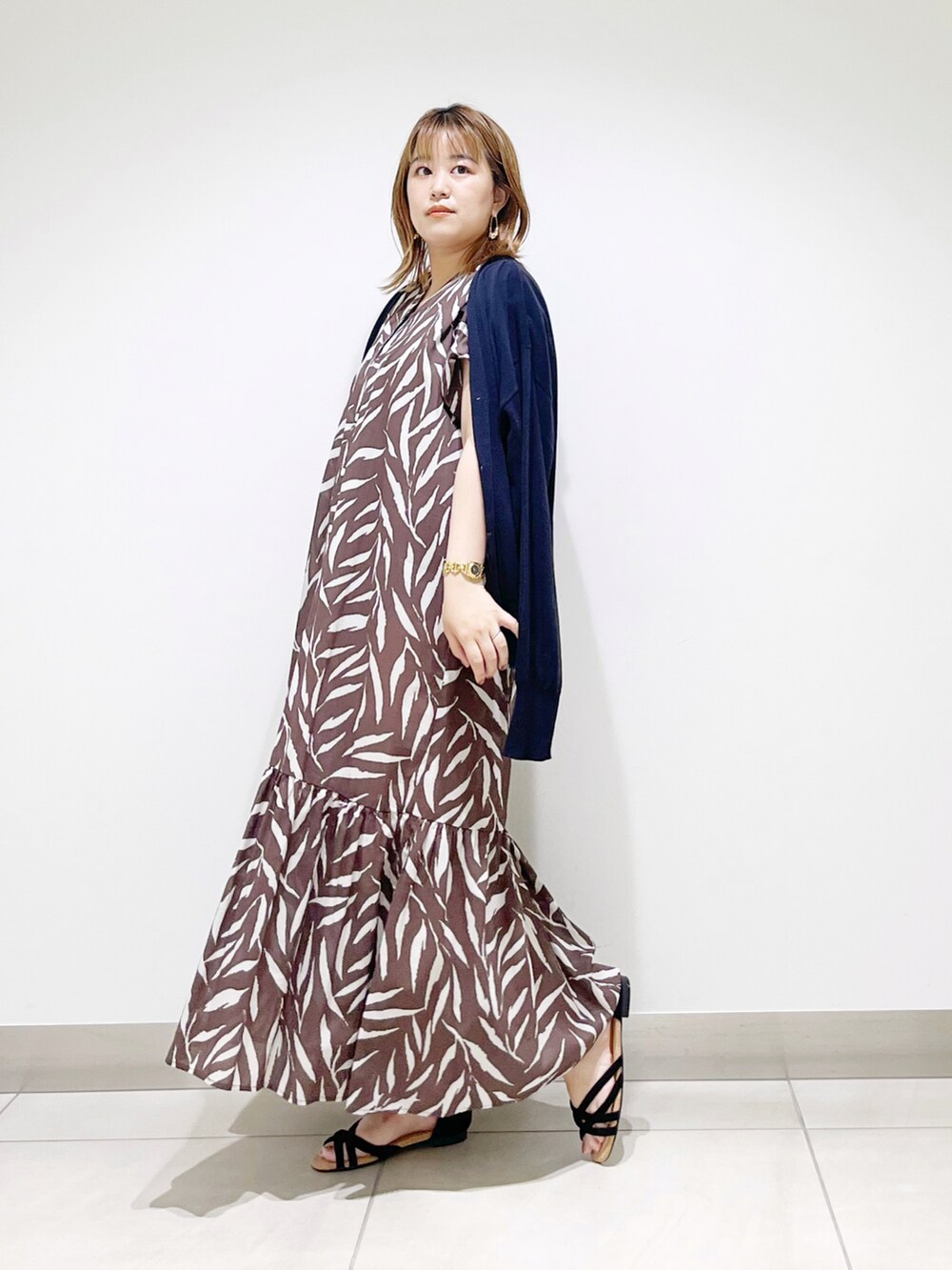 ブラウン系のワンピース、ベージュ系のハンドバッグ、ブラック系のサンダルを着用したレディースの夏コーディネートの2枚目の写真