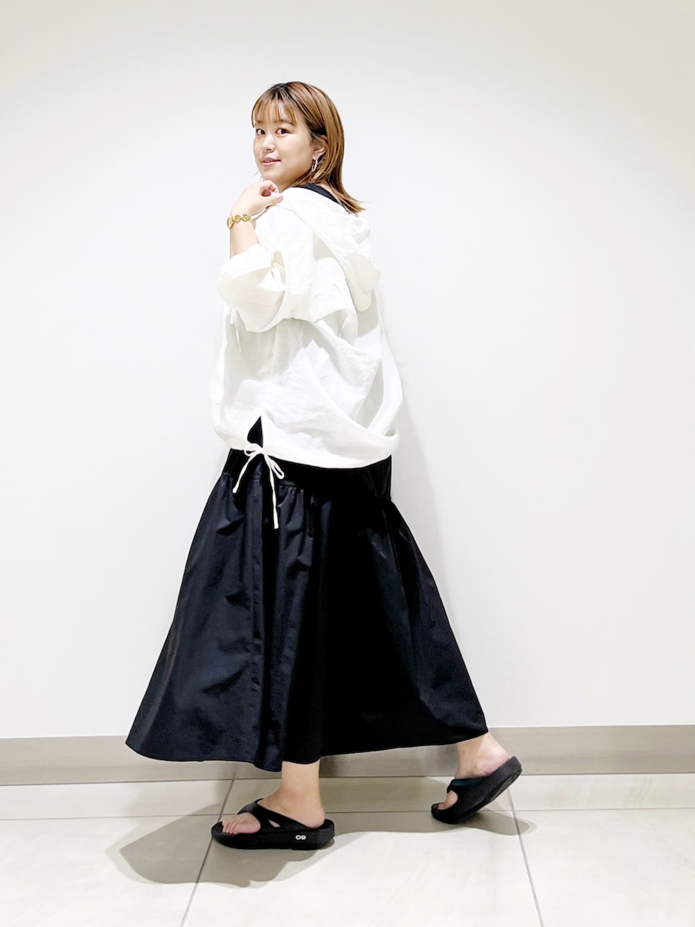 ホワイト系のパーカー、ブラック系のスカート、ブラック系のショルダーバッグを着用したレディースの夏コーディネートの2枚目の写真